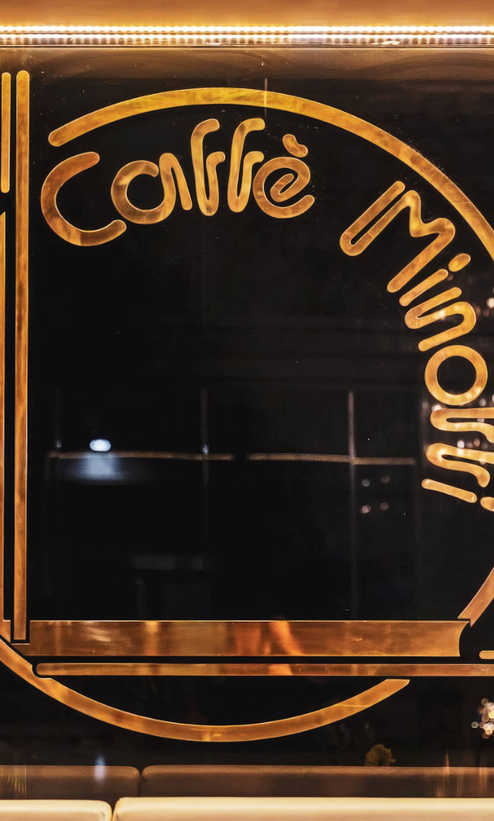 L'insegna in ottone del Caffè Minotti nel vetro, con il monogramma e la scritta
