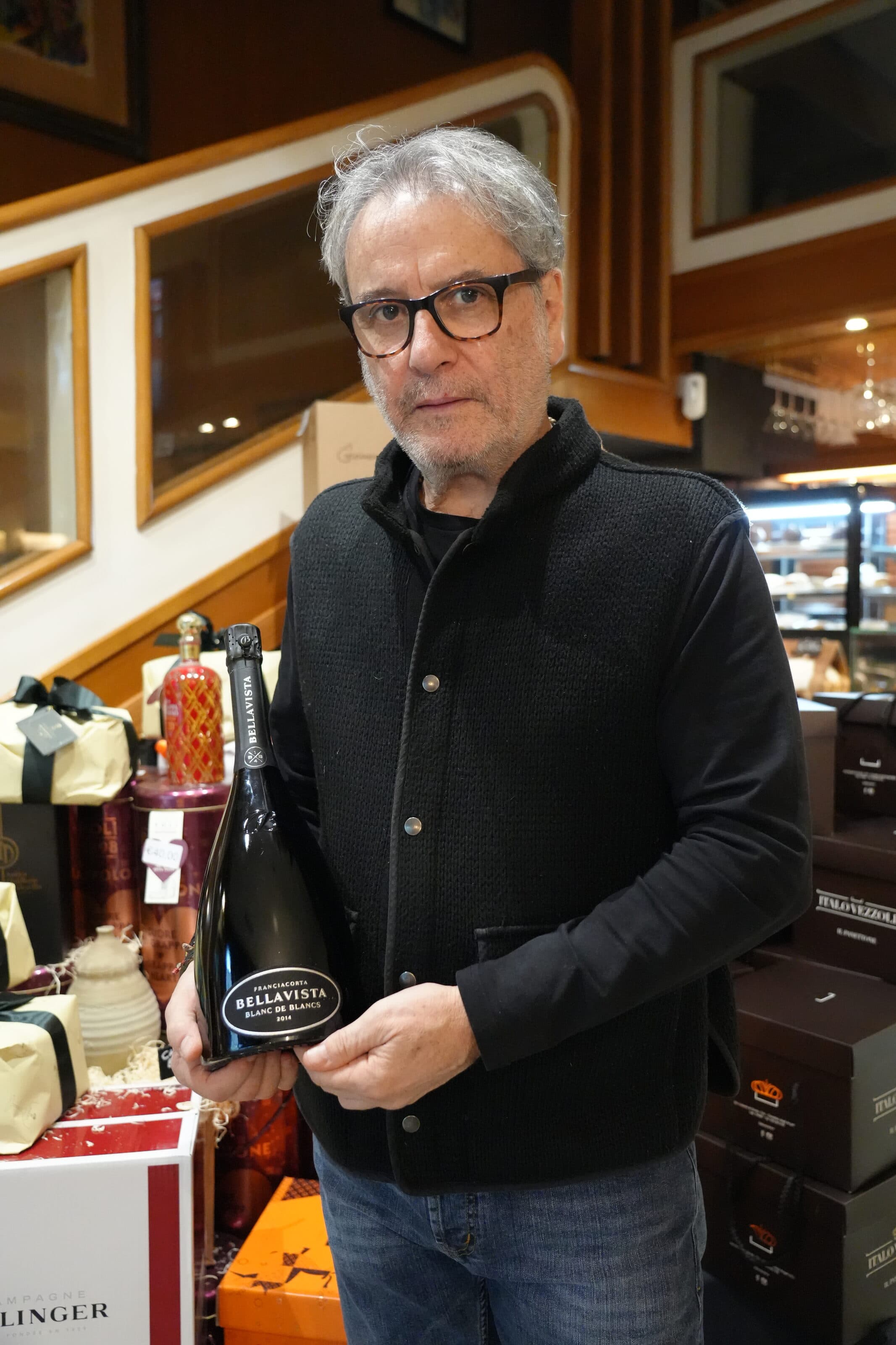 Vincenzo Minotti nel locale, con una bottiglia di Franciacorta